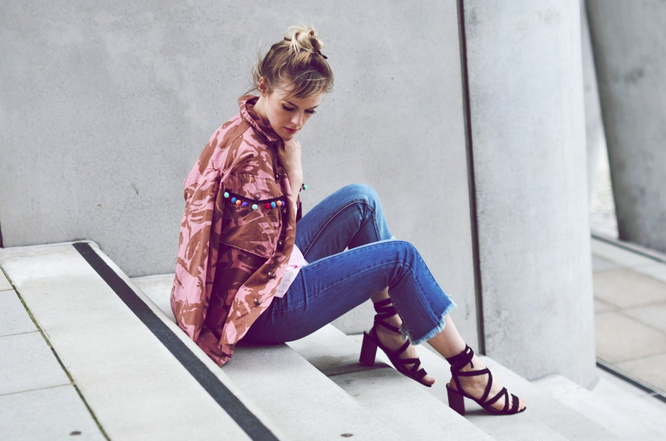 stairs, pink camouflage jacket, colored tassels, blue jeans, black sandals
